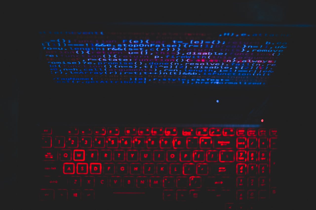 about-us Dark-themed laptop setup with a red glowing keyboard and code on screen, ideal for tech enthusiasts.