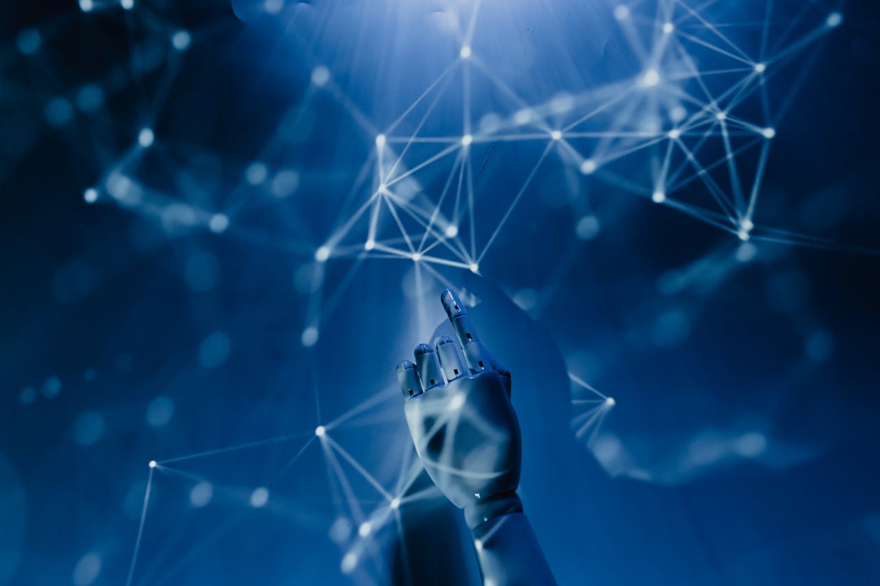 heros-img A robotic hand reaching into a digital network on a blue background, symbolizing AI technology.